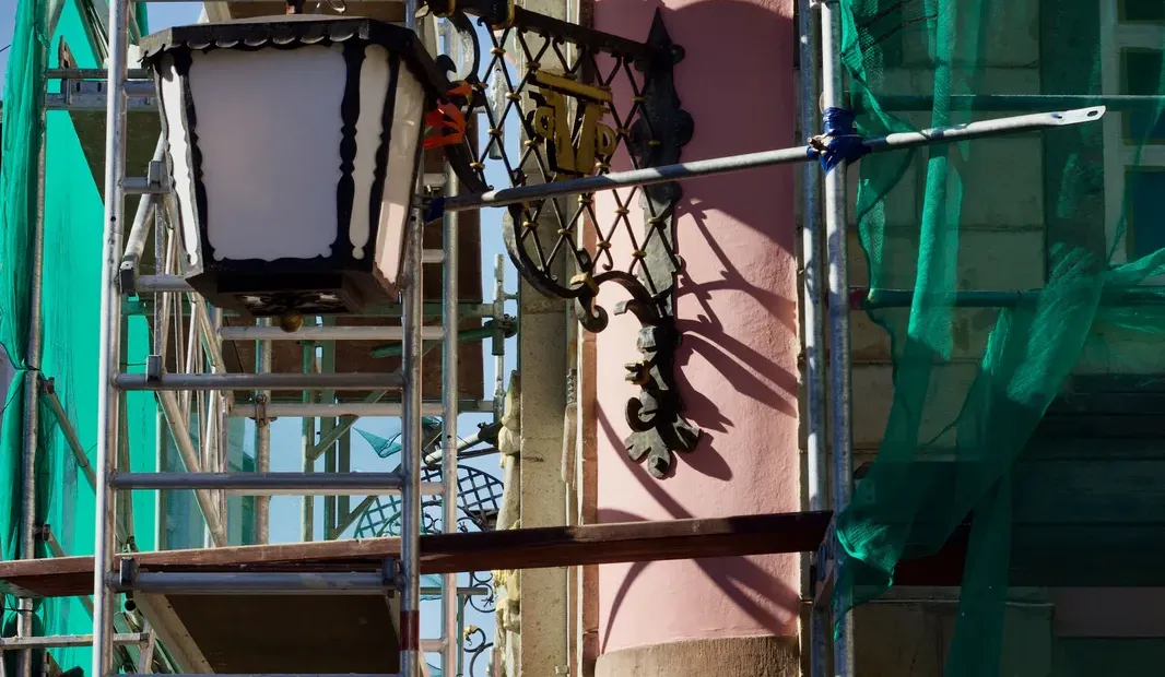 Edificio de una comunidad de propietarios en rehabilitación de fachada con andamios, obra subvencionada que no computa como ingreso para el Ingreso Mínimo Vital según la STS 56/2026