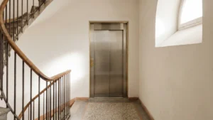 Pasillo interior de edificio residencial español con ascensor y escalera, ilustrativo de la STS 2920/2025 sobre exención de cuotas del ascensor en comunidades de propietarios